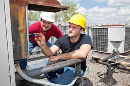 2 Hvac Technicians diagnosing issues of an air conditioning unit in Victoria BC on a rooftop