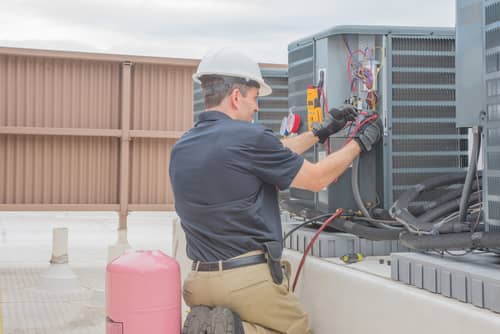 Picture of a HVAC technician working on a rooftop unit in Victoria